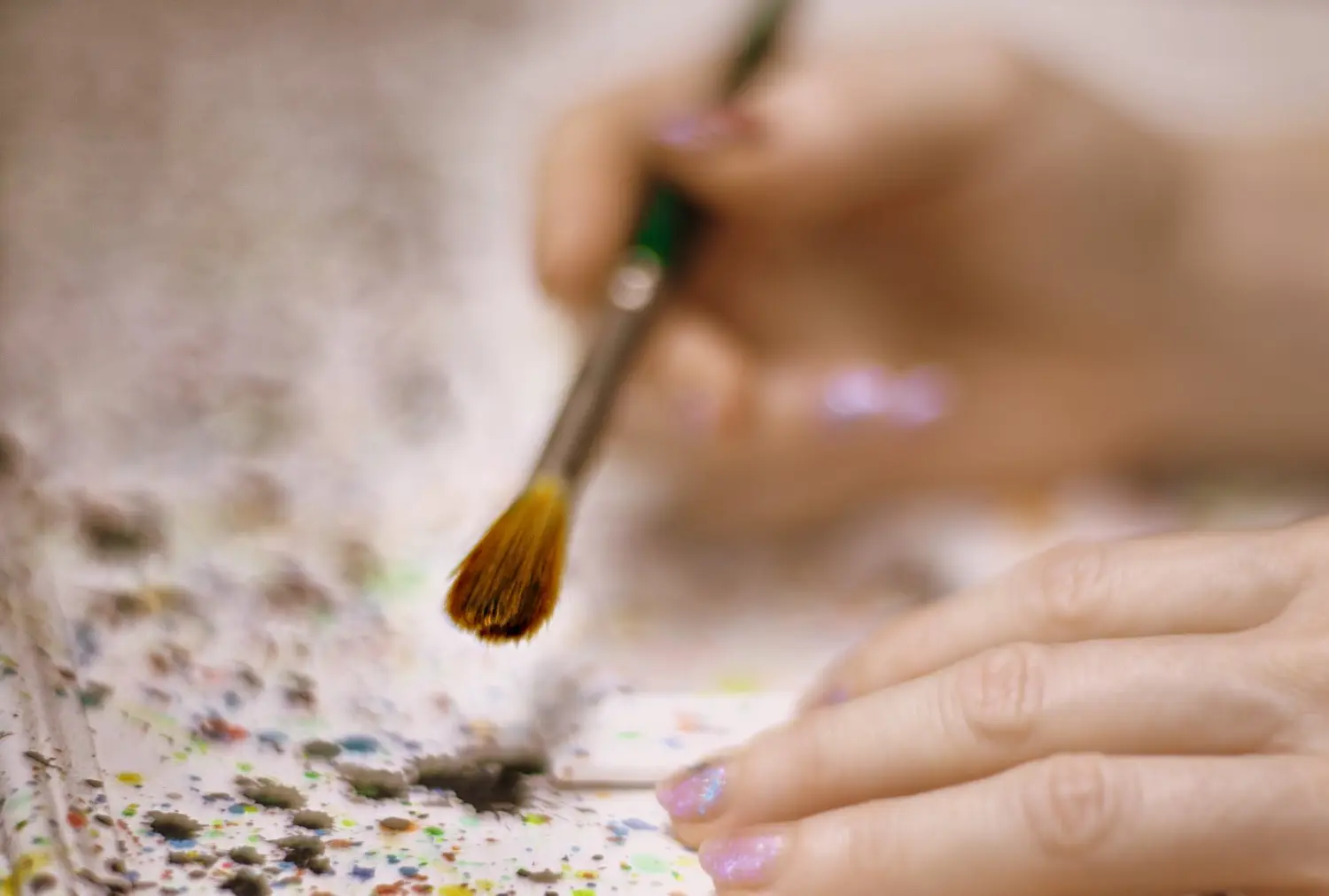 Art Fabric – Kunstgalerie – Nahaufnahme einer Person, die mit Pinsel und Palette malt.